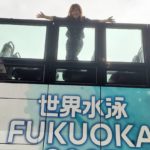 世界水泳FUKUOKA2023仕様のオープントップバスの上に女性