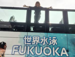 世界水泳FUKUOKA2023仕様のオープントップバスの上に女性