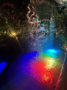 滝が流れ込む池にレインボーのライトアップ