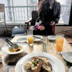 椅子に座る女性の前のテーブルの上にジュースと料理