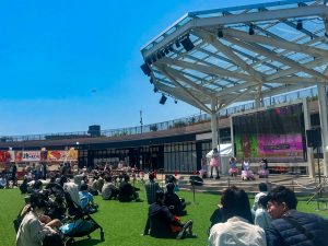 青空の下、ステージで踊る縁者と観客